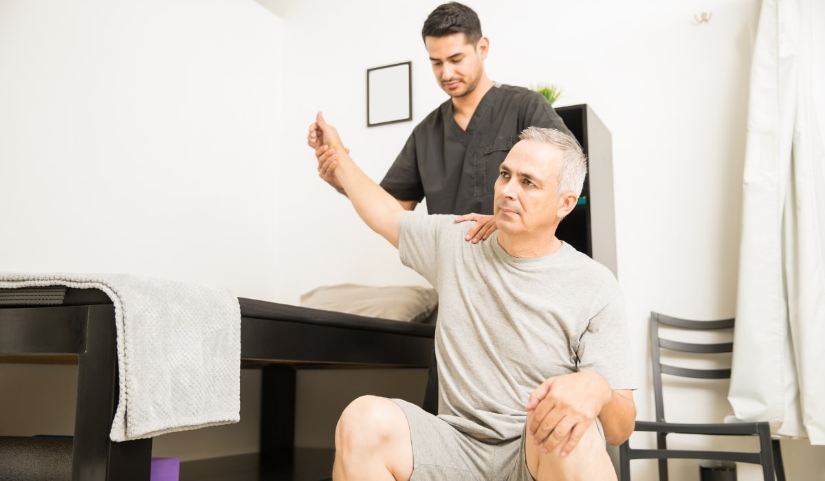 a man having his arm and shoulder mobility tested by a physical therapist