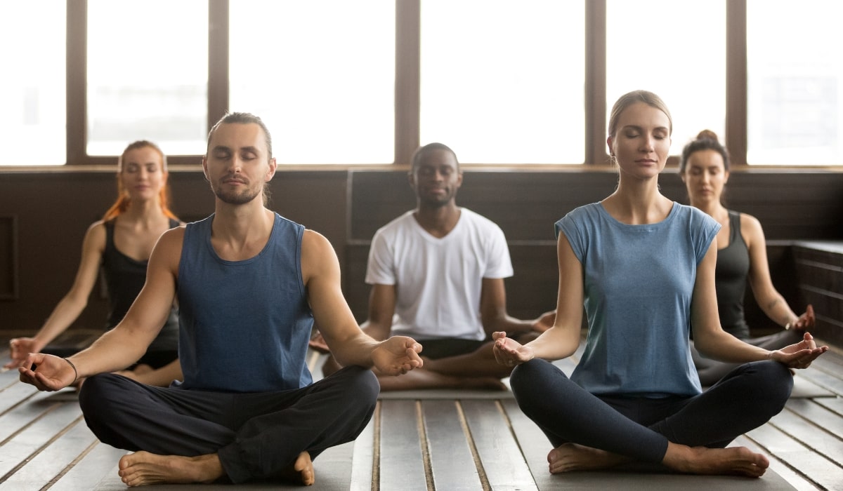 a group of people sitting and doing group yoga