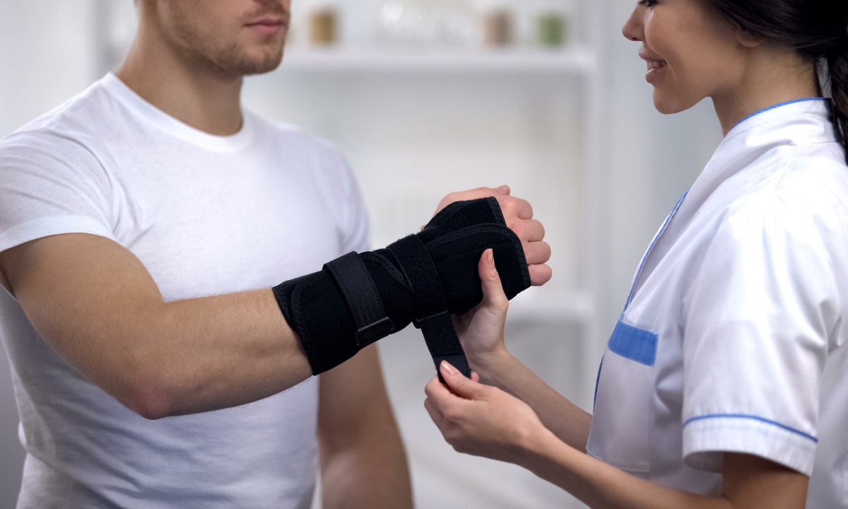 a doctor helping a patient put on a wrist brace
