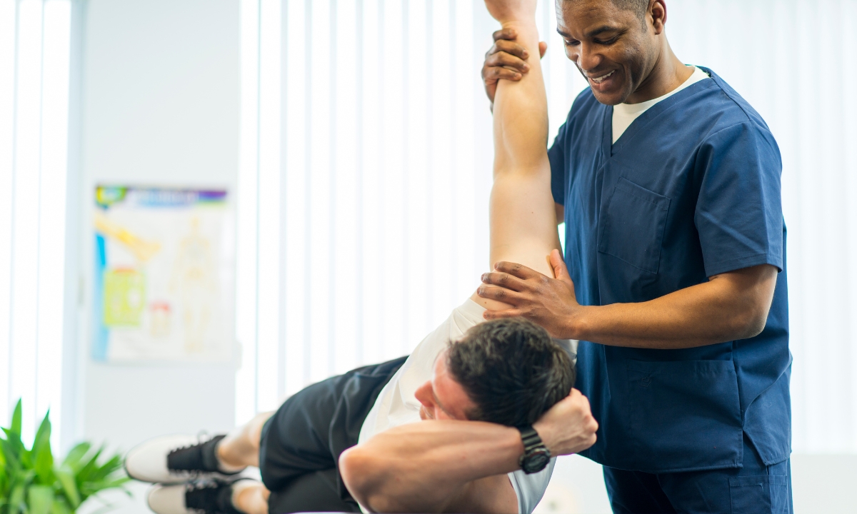 a physical therapist helping a person rotate their shoulder