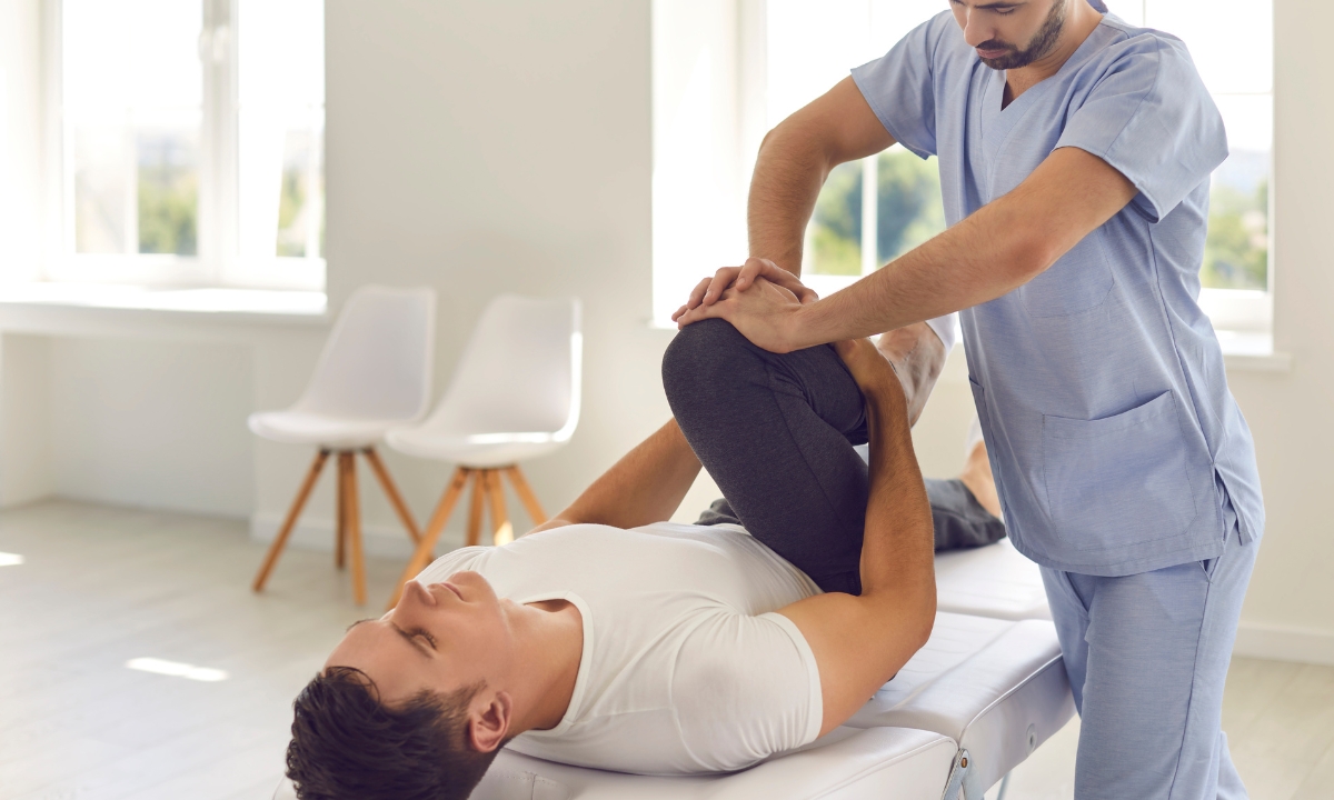 a physical therapist helping their patient stretch their hamstring