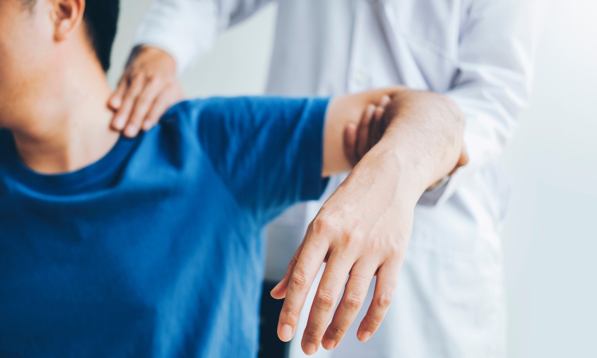 a physical therapist helping their patient stretch their arm and shoulder