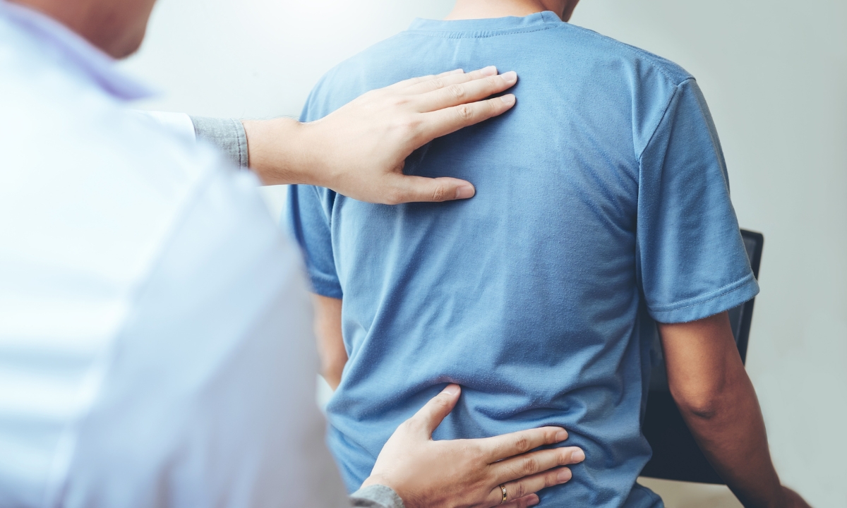 a physical therapist touching a patient's back 