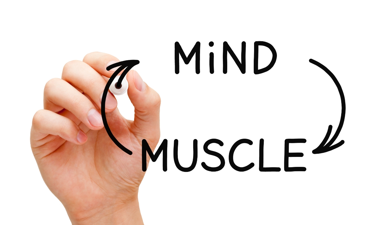 a person's hand writing out "mind" and "muscle"  with arrows comng out from near each word and pointing around to the next word