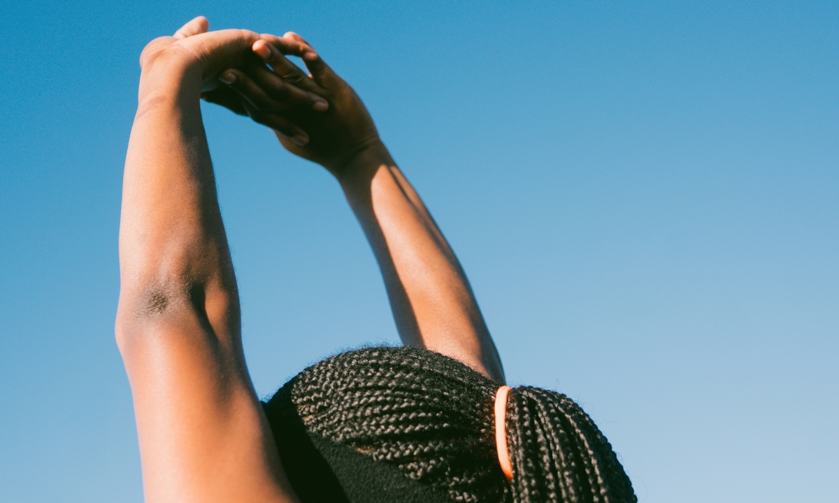 a person's arms stretched up towards the sky with their hands intertwined and facing away