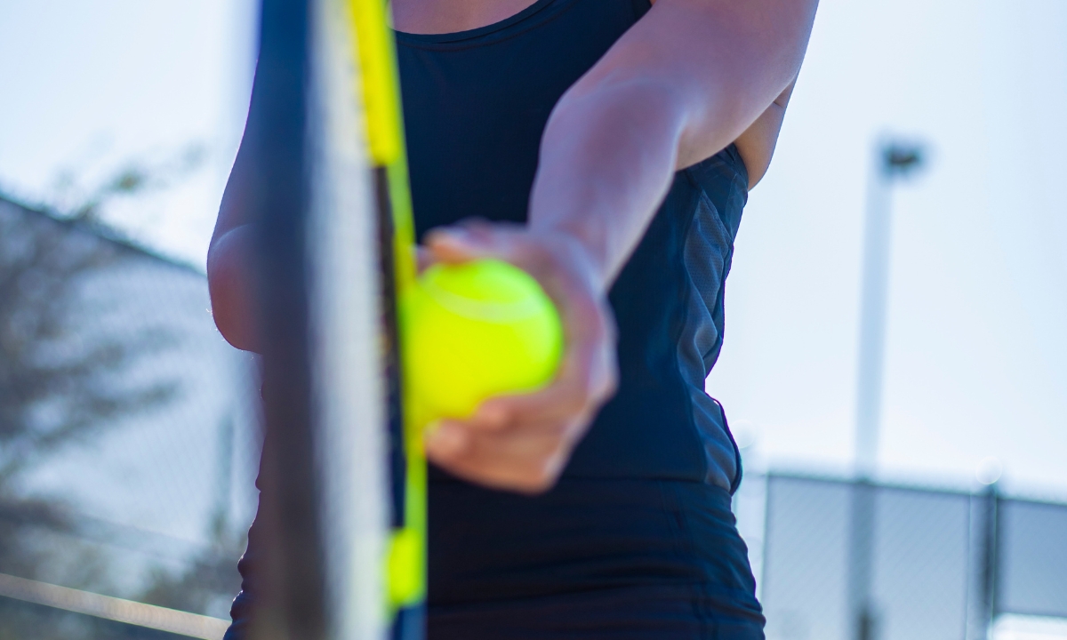 an image zoomed in and focused on a tennis racket and ball in a person's hand