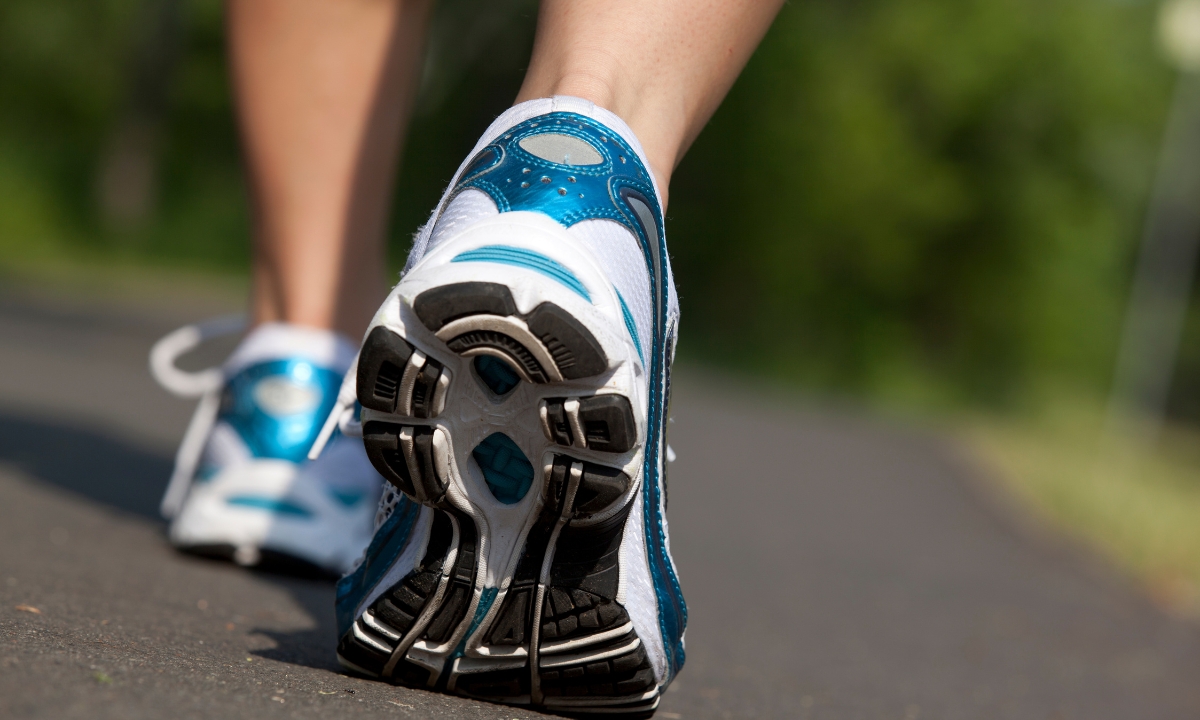 a shot of a person's shoes walking down a road